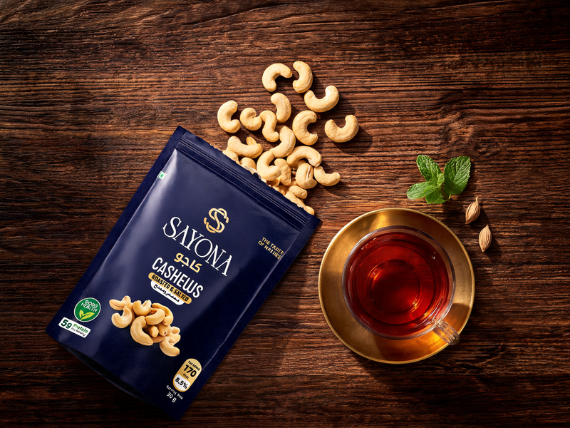 Sayona Cashews pouch with cashews spilling out next to a glass of tea